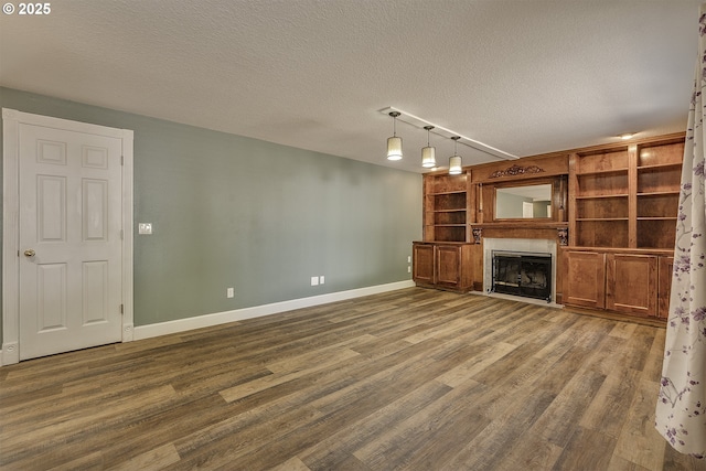 9373 SW Fast Pl, Portland, OR 97223 - unfurnished living room featuring wood finished floors, a textured ceiling, a fireplace, and built in shelves