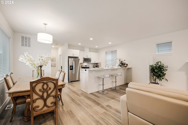 dining space with baseboards, light wood-style flooring, visible vents, and recessed lighting