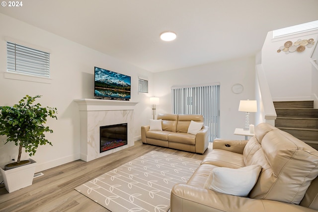 living room featuring a fireplace, visible vents, wood finished floors, baseboards, and stairs