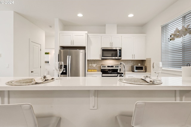 kitchen featuring light countertops, appliances with stainless steel finishes, white cabinets, and tasteful backsplash