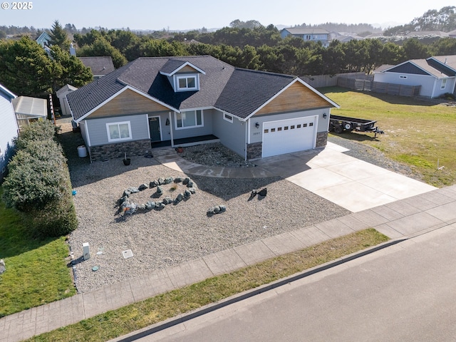 craftsman inspired home with concrete driveway, a front yard, fence, a garage, and stone siding