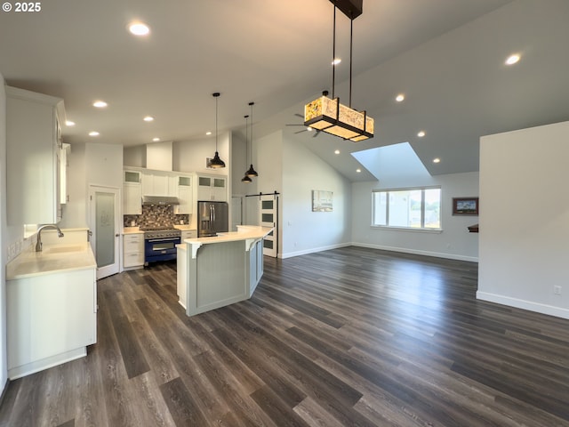 kitchen with light countertops, appliances with stainless steel finishes, a barn door, and white cabinetry