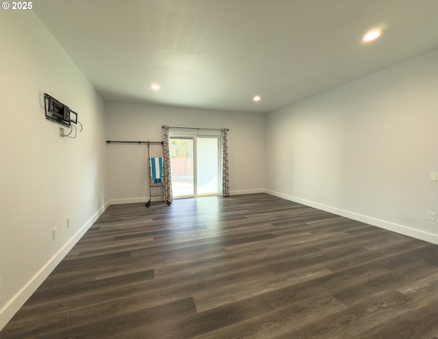 empty room with an AC wall unit, dark wood-style flooring, recessed lighting, and baseboards