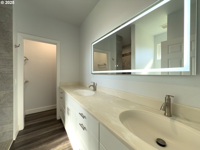 bathroom with double vanity, wood finished floors, a sink, and visible vents