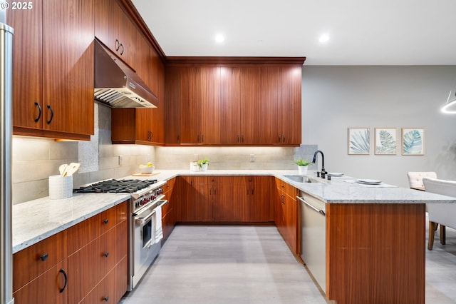 kitchen featuring appliances with stainless steel finishes, a sink, light stone countertops, a peninsula, and extractor fan