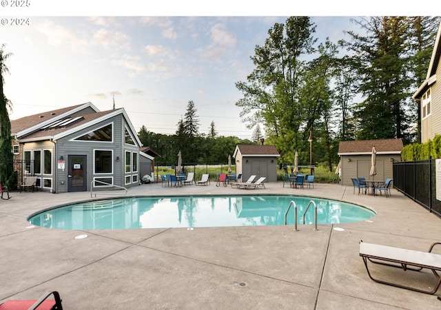 pool with a storage shed, a patio, and fence