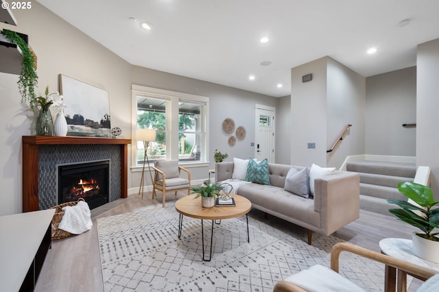 living area with a fireplace, recessed lighting, light wood-style floors, baseboards, and stairs