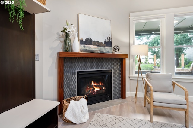 living area with a tile fireplace, baseboards, and wood finished floors