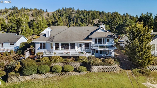 back of property featuring a wooden deck, a yard, and a balcony