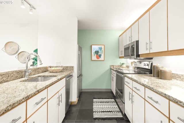 1710 S Harbor Way Unit 201, Portland, OR 97201 - kitchen with appliances with stainless steel finishes, a sink, dark tile patterned floors, white cabinetry, and light stone counters