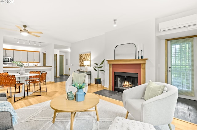 1710 S Harbor Way Unit 201, Portland, OR 97201 - living room featuring a wall mounted AC, a fireplace with flush hearth, a ceiling fan, and light wood-type flooring