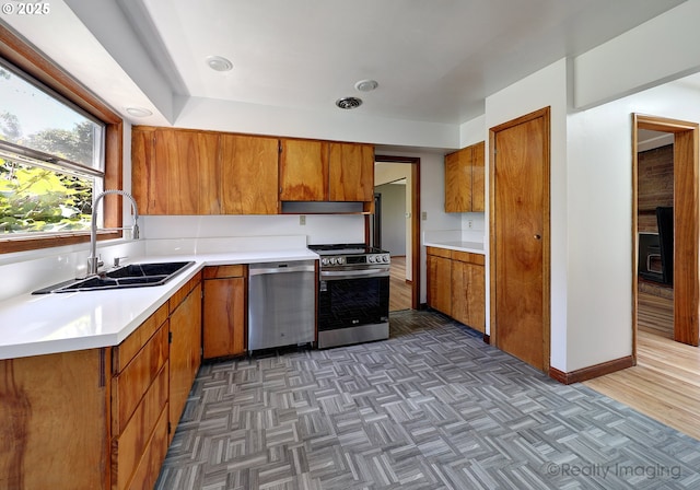 5730 N Harvard St, Portland, OR 97203 - kitchen featuring stainless steel appliances, a sink, brown cabinetry, light countertops, and parquet flooring