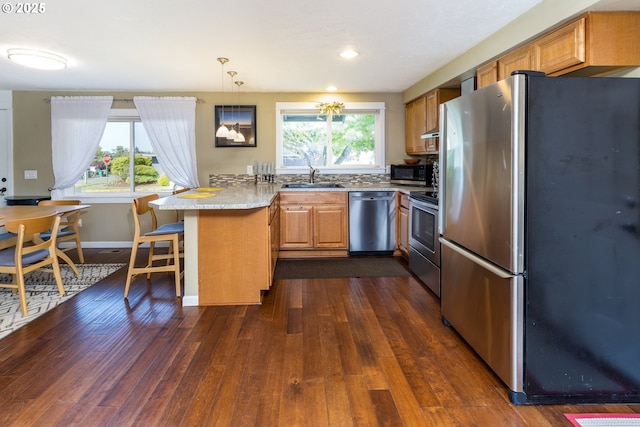 kitchen with a sink, baseboards, a peninsula, dark wood-style floors, and stainless steel appliances