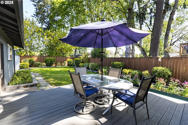 deck with a fenced backyard, outdoor dining space, and a lawn