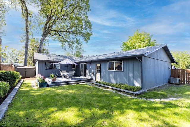 rear view of property featuring a lawn, a deck, and fence