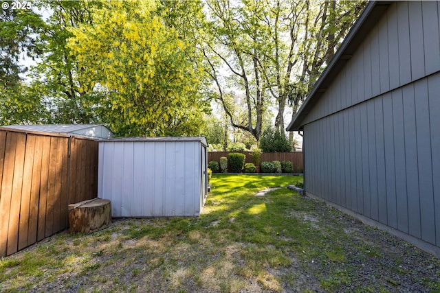 view of yard with a storage unit, a fenced backyard, and an outbuilding