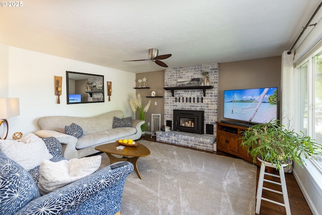 living area featuring a ceiling fan, baseboards, wood finished floors, and a fireplace