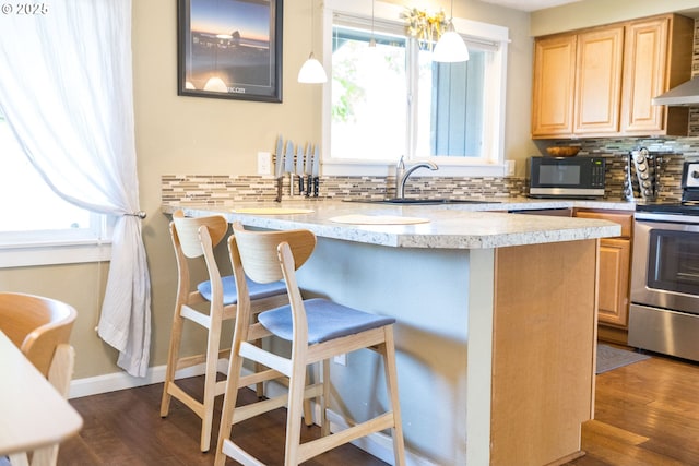 kitchen with a breakfast bar area, black microwave, light brown cabinetry, stainless steel range with electric stovetop, and a sink
