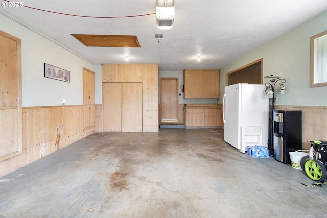 1311 NE 116th Ave, Portland, OR 97220 - garage featuring freestanding refrigerator, wooden walls, wainscoting, and a garage door opener