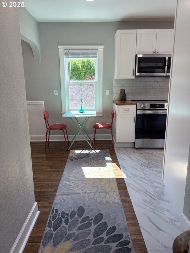 708 W 28th St, Vancouver, WA 98660 - kitchen with appliances with stainless steel finishes, white cabinetry, tasteful backsplash, and arched walkways