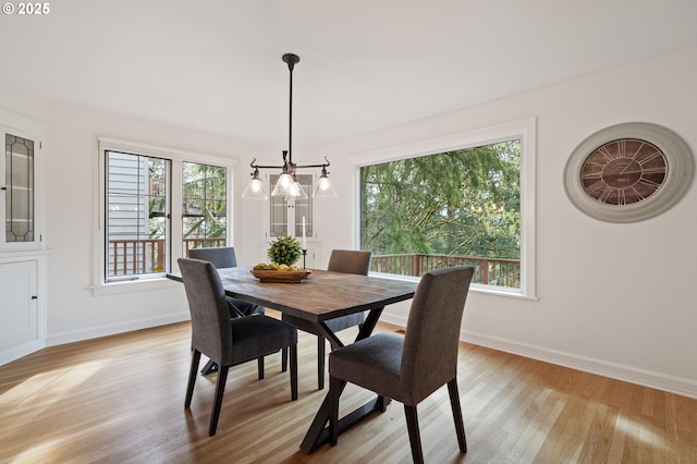 dining room with a wealth of natural light, light wood finished floors, and a chandelier