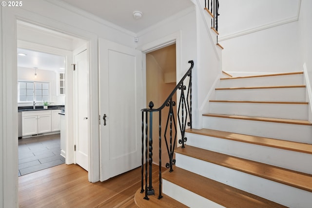 staircase with ornamental molding and wood finished floors