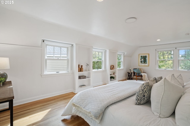 bedroom with baseboards, lofted ceiling, and wood finished floors