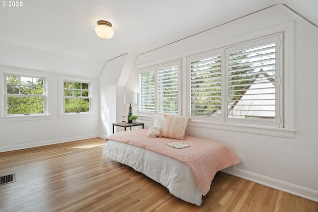 bedroom featuring visible vents, wood finished floors, baseboards, and lofted ceiling