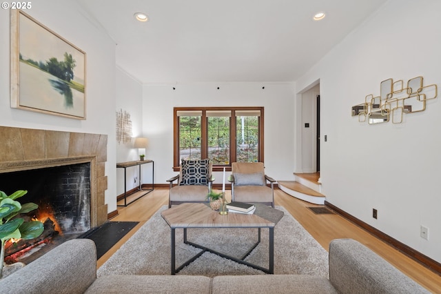 living area with light wood-style floors, a tiled fireplace, baseboards, and visible vents