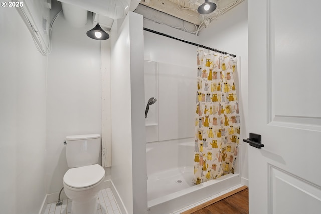 bathroom with baseboards, toilet, and a stall shower