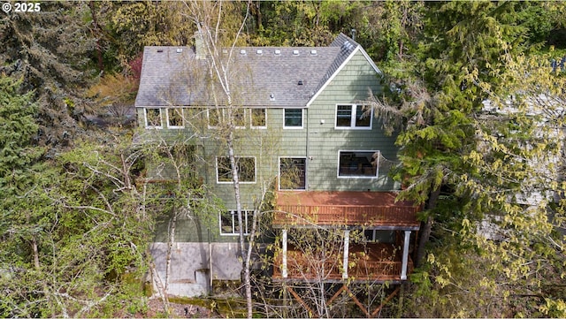 back of house featuring roof with shingles and a deck