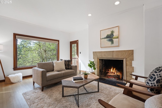 living room with baseboards, a tile fireplace, recessed lighting, and wood finished floors
