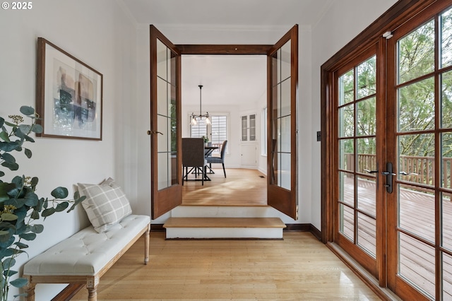 entryway with baseboards, light wood finished floors, french doors, and a chandelier