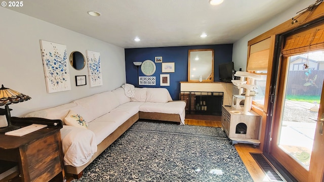 living area featuring a brick fireplace, wood finished floors, visible vents, and recessed lighting