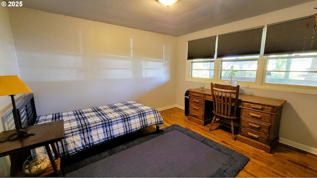 bedroom featuring multiple windows, baseboards, and wood finished floors