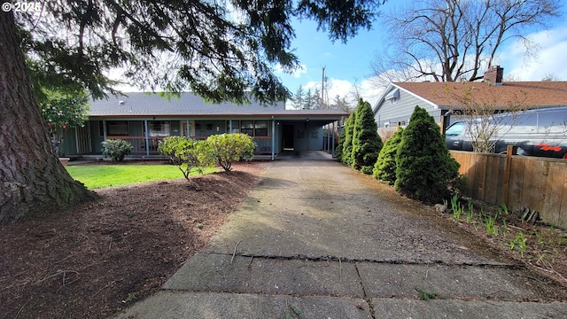 view of front of home featuring driveway, fence, and a carport