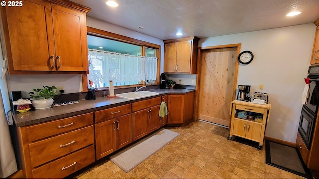 kitchen with brown cabinetry, dark countertops, a sink, and baseboards