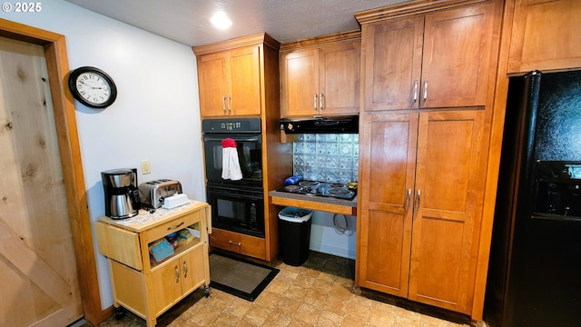 kitchen featuring brown cabinets, a toaster, under cabinet range hood, and black appliances