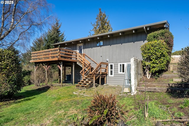 rear view of property with a lawn, a deck, and stairs