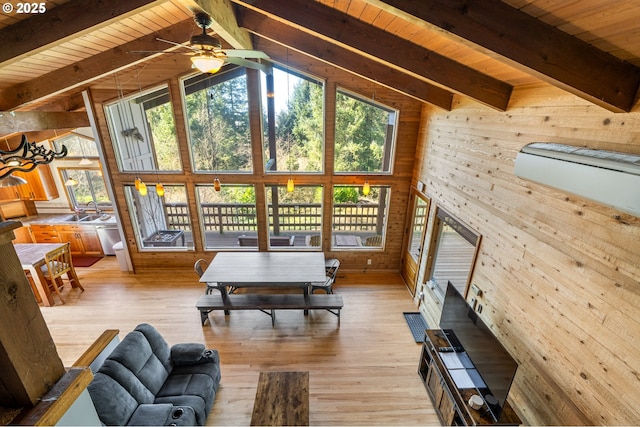 living room featuring wood walls, light wood-style floors, and beamed ceiling