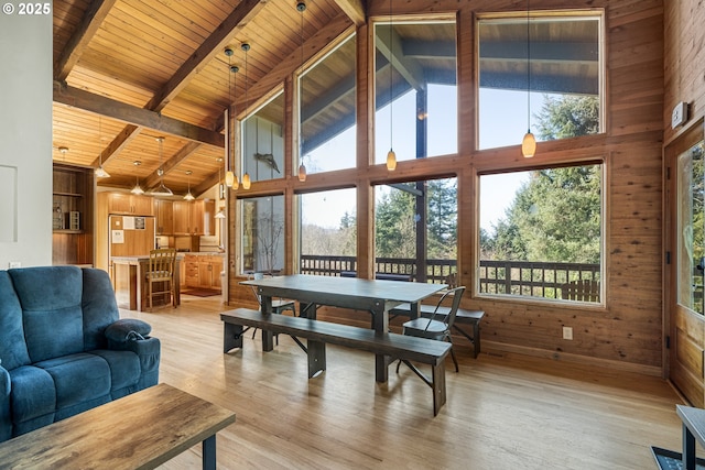 dining area with beam ceiling, wooden walls, high vaulted ceiling, light wood-type flooring, and wooden ceiling