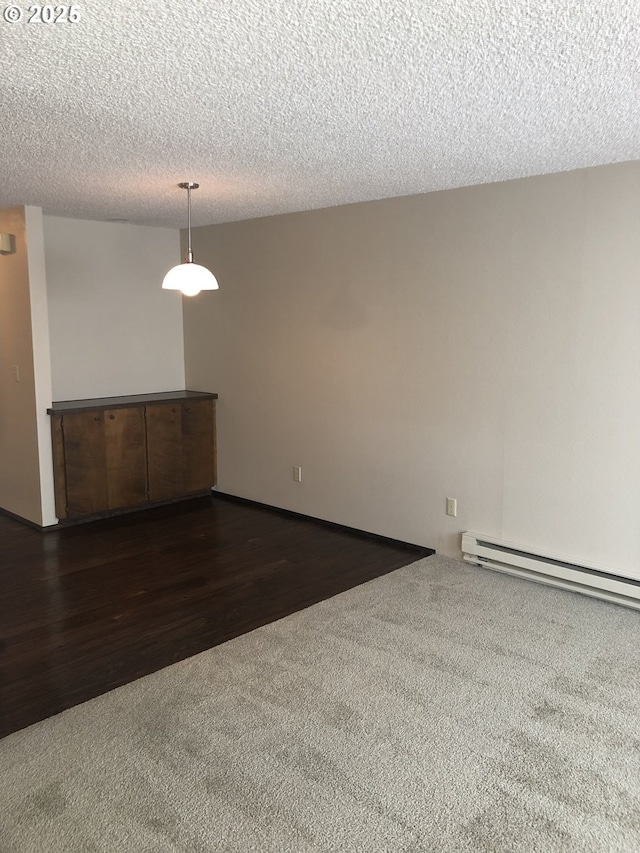 323 S Locust St, Canby, OR 97013 - empty room featuring dark carpet, a baseboard heating unit, a textured ceiling, and dark wood-style flooring