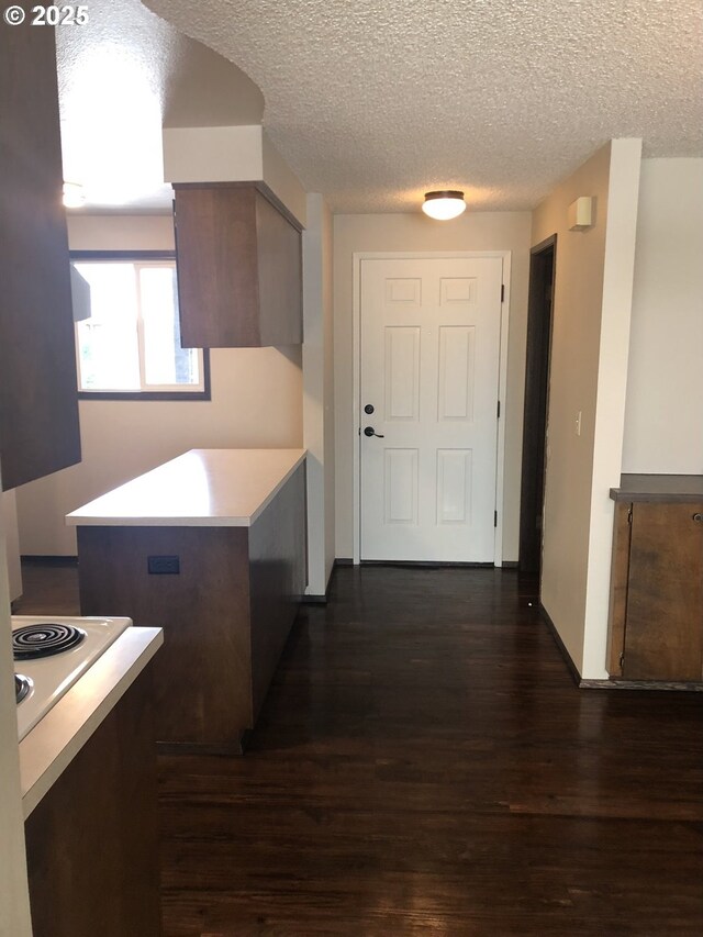 323 S Locust St, Canby, OR 97013 - kitchen with dark wood-type flooring, a textured ceiling, light countertops, stove, and a peninsula