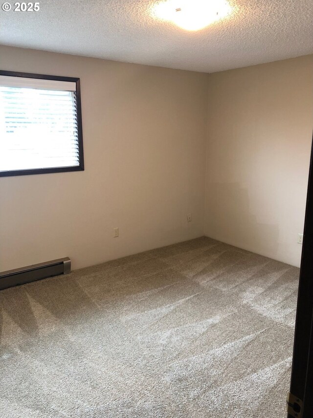 323 S Locust St, Canby, OR 97013 - empty room featuring carpet, a textured ceiling, and a baseboard heating unit