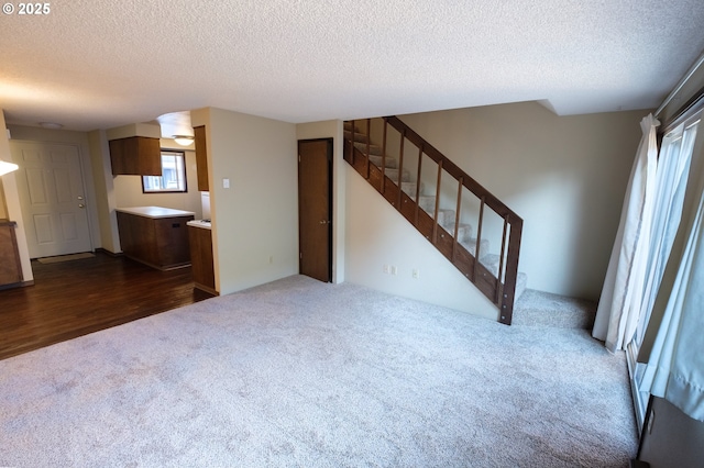 323 S Locust St, Canby, OR 97013 - unfurnished living room featuring dark colored carpet, stairway, a textured ceiling, and dark wood-style flooring