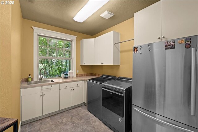 12521 NW Jackson Quarry Rd, Hillsboro, OR 97124 - kitchen with freestanding refrigerator, washer and clothes dryer, a sink, white cabinetry, and light countertops