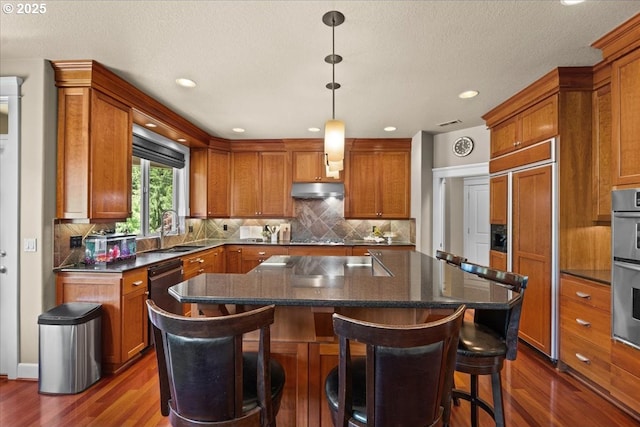 12521 NW Jackson Quarry Rd, Hillsboro, OR 97124 - kitchen featuring a sink, dark wood-style floors, under cabinet range hood, brown cabinets, and recessed lighting