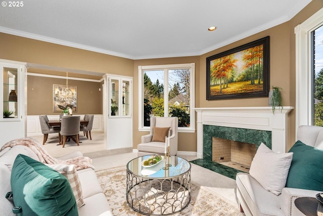 carpeted living area with crown molding, a notable chandelier, recessed lighting, and a high end fireplace
