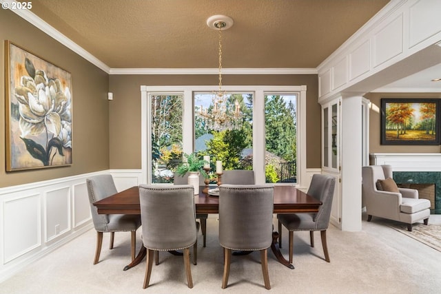 dining space featuring ornamental molding, a textured ceiling, a decorative wall, light colored carpet, and a chandelier