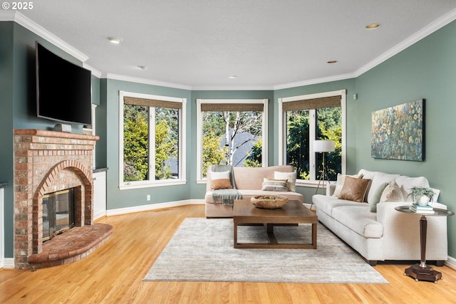 living room with a brick fireplace, crown molding, baseboards, and wood finished floors